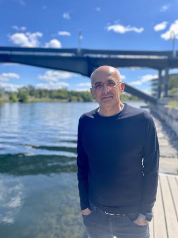 Professor standing on a dock in front of the bridge