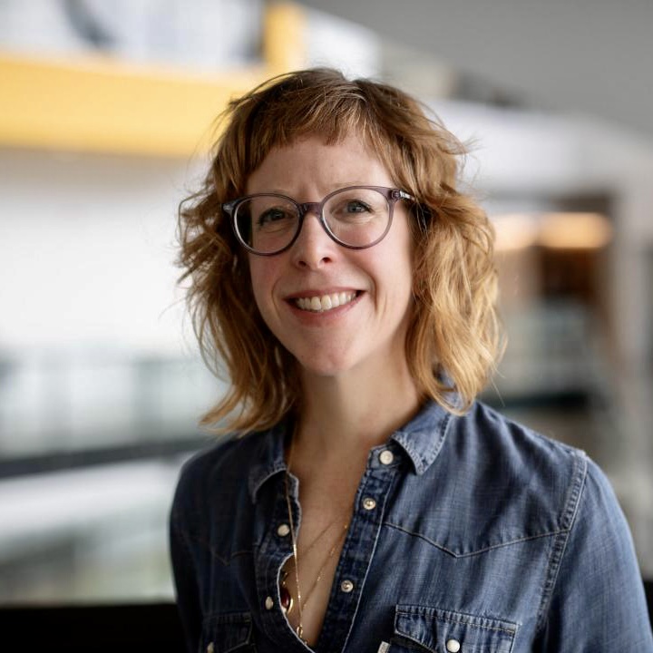 white woman, red hair, blue shirt, smiling, glasses
