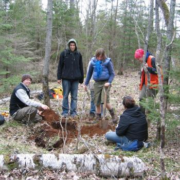students digging hole in ground in forest in Trent Nature Area