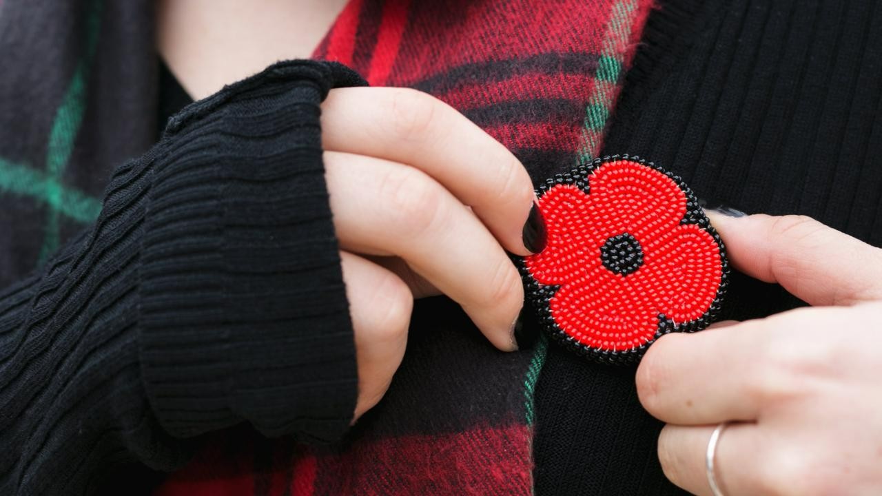 A person wearing a beaded poppy.