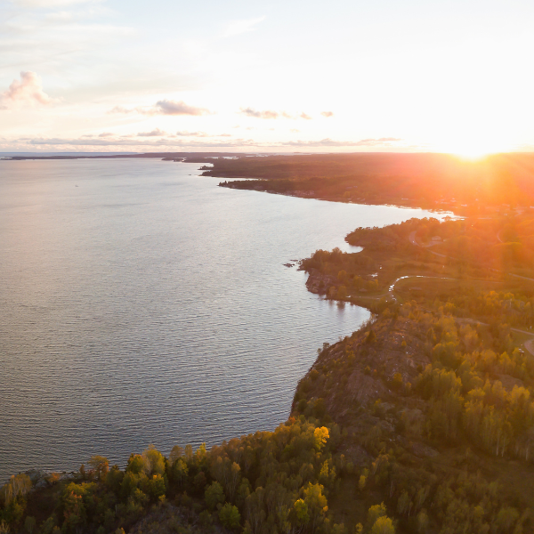 A body of water next to some land on the right at sunset