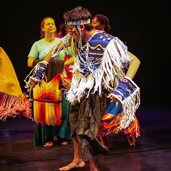 Students in regalia dancing on stage in the Performance Space