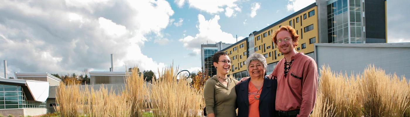 Shirley Williams standing outside in front of Gzowski College with two Ph.D. students