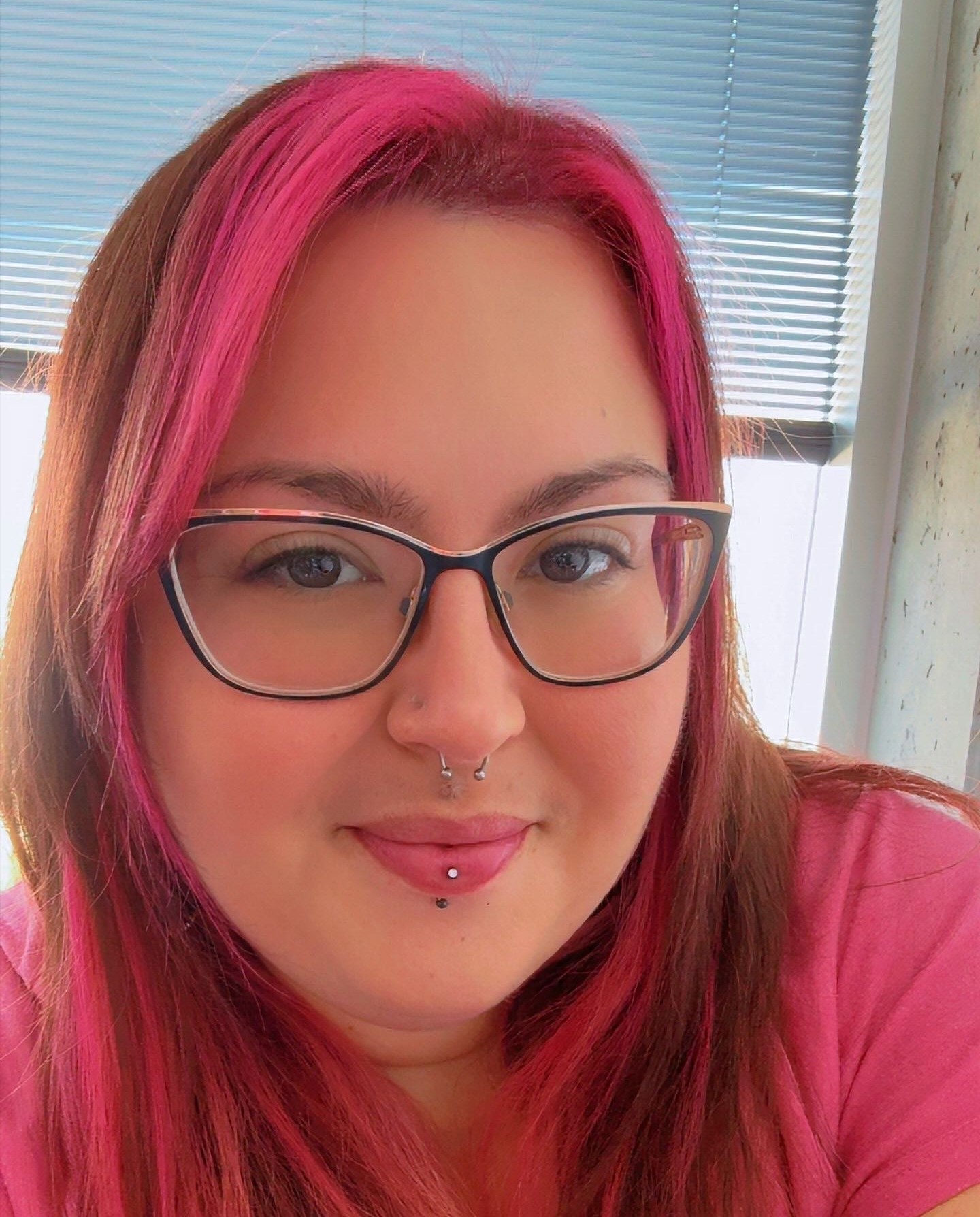 Woman with pink hair and pink shirt smiling.