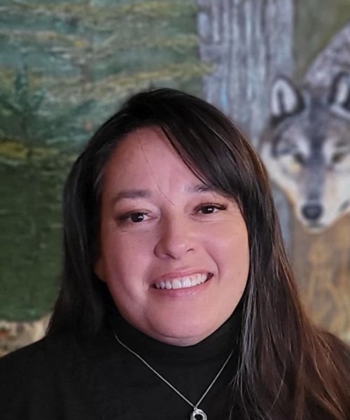 Woman smiling with wolf image in background.
