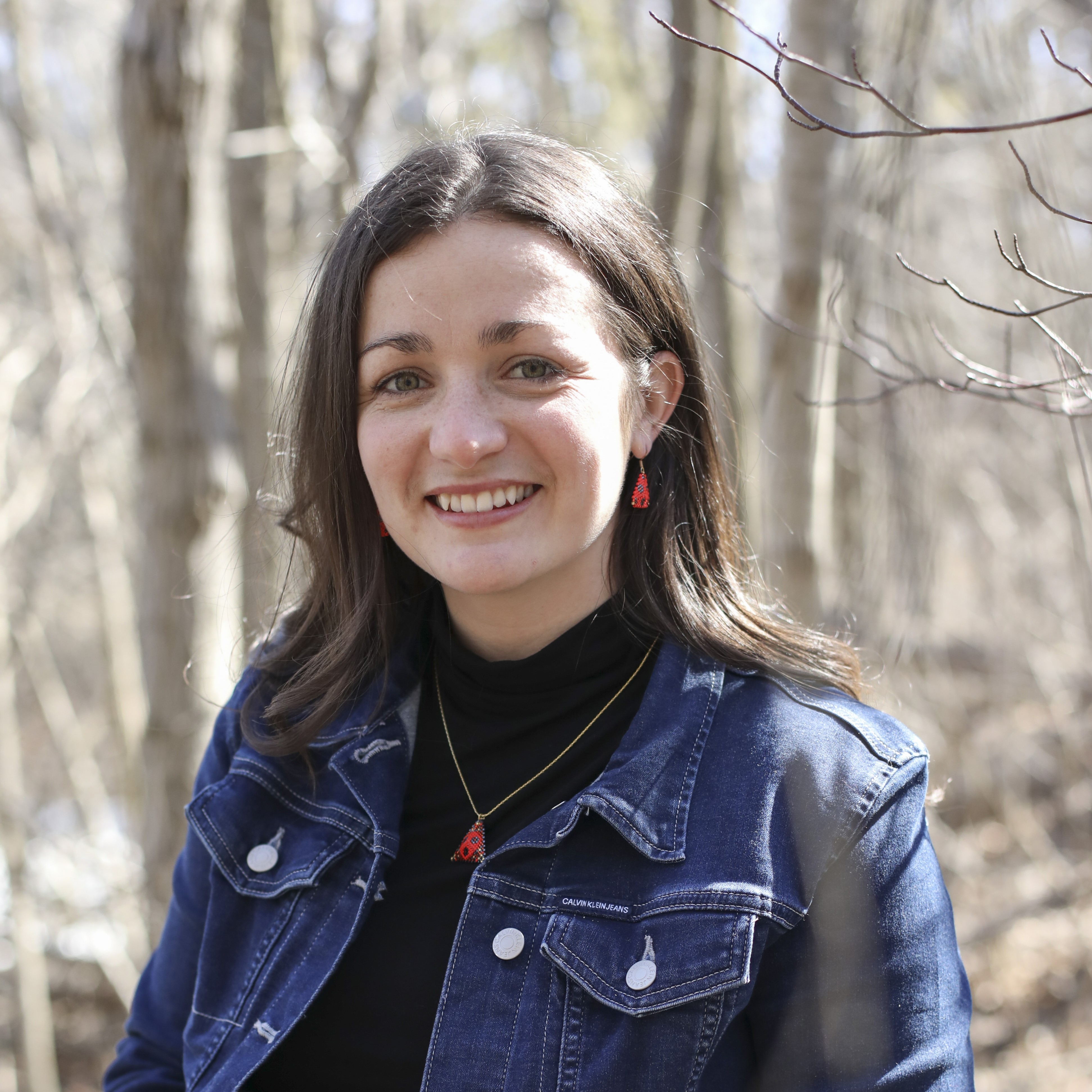 Woman smiling with sunlight shining on her hair in woods.