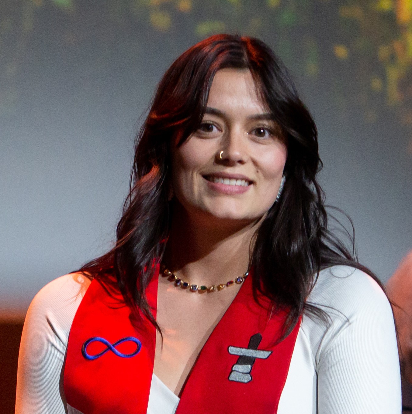 Smiling woman with dark long hair and red scarf.