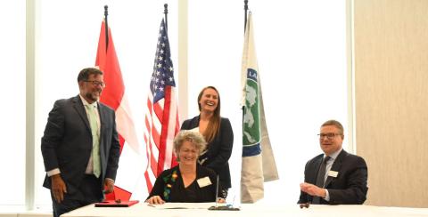 Dr. Barbara Moktthenwenkwe Wall signing document between Great Lakes Fishery Commission and Trent University with Dr. Mary-Claire Buell and Dr. Marc Gaden.