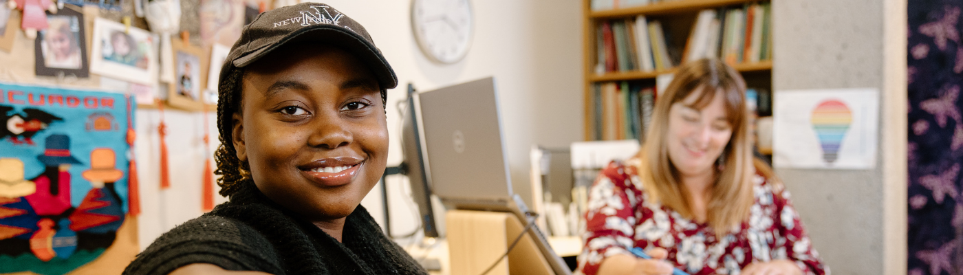 Student smiling into the camera next to a support staff