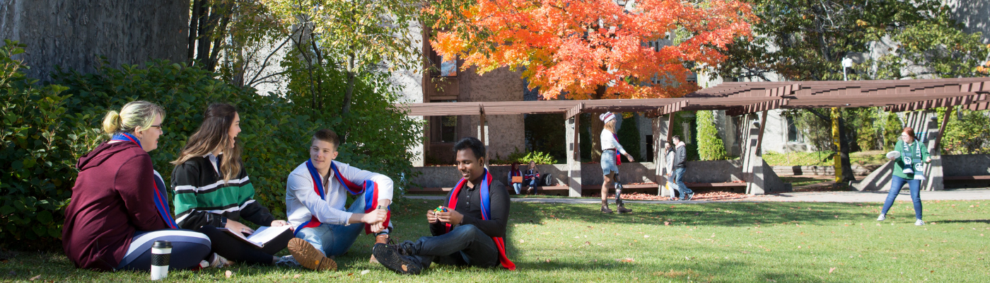 Group of students sitting on the grass outside of Champlain College