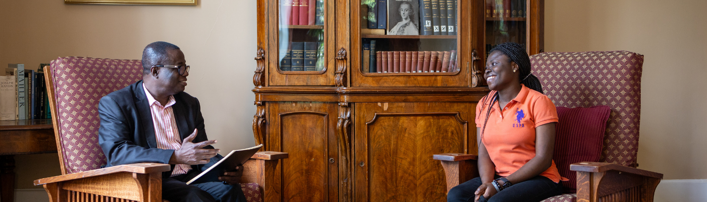 A professor and student sitting in a room speaking together