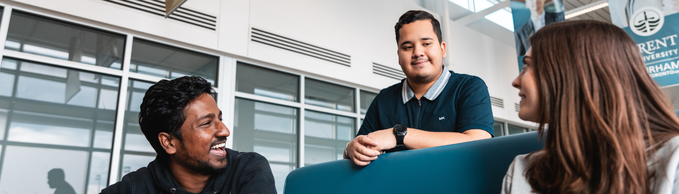 Three students sitting at a table and laughing