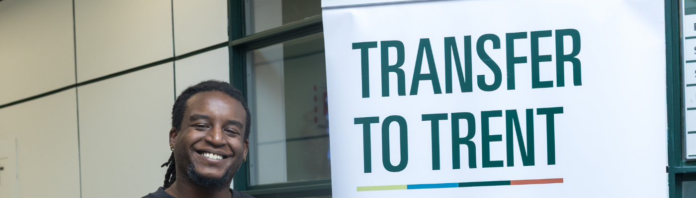 Man smiling next to a sign that says Transfer to Trent