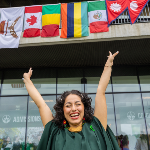 Trent graduate standing in front of flags from various countries