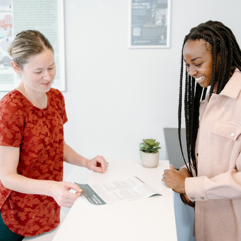 A student standing at a desk receiving career support from a Trent staff member
