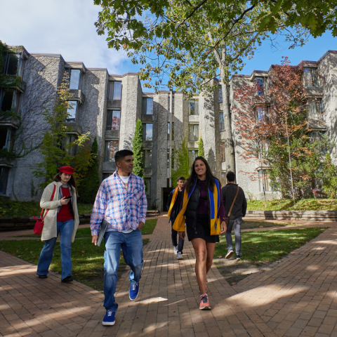 Students walking outside of a stone building covered in vines