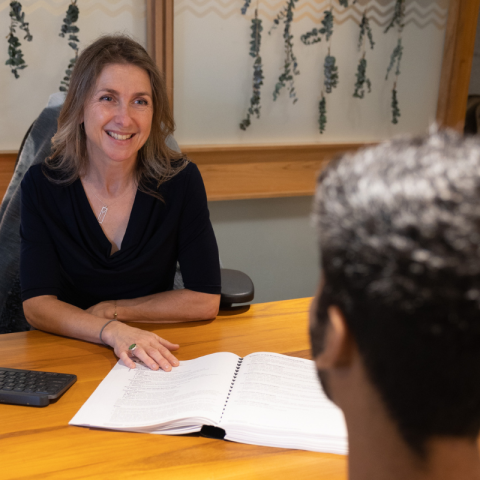Trent staff passing paper across a desk to a student