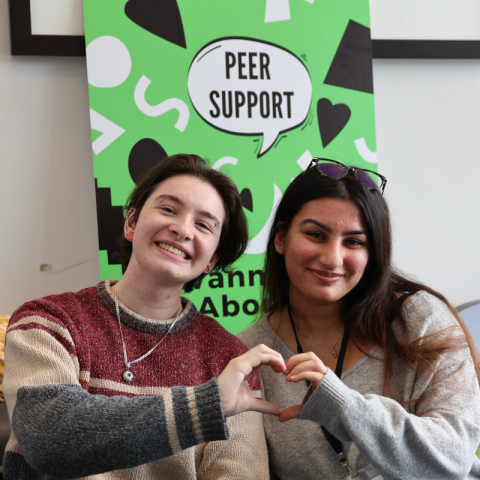 Two students putting their hands together to make a heart shape