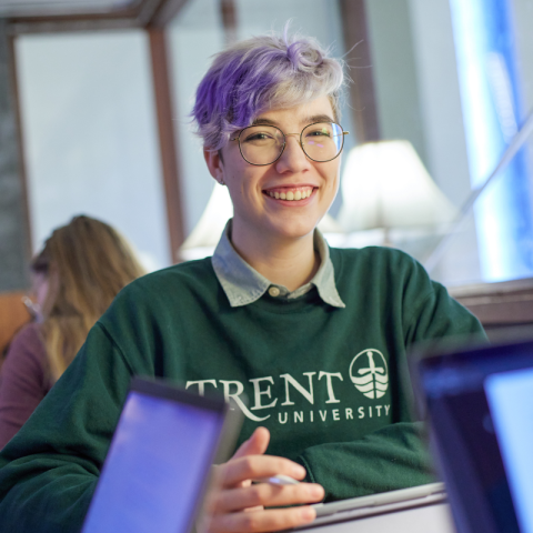 Student holding a pen and smiling