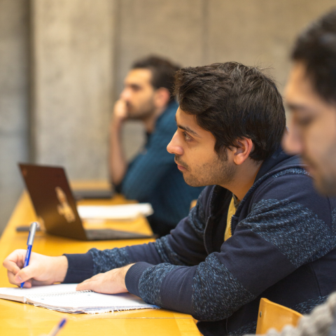 Student writing notes in a notebook during class