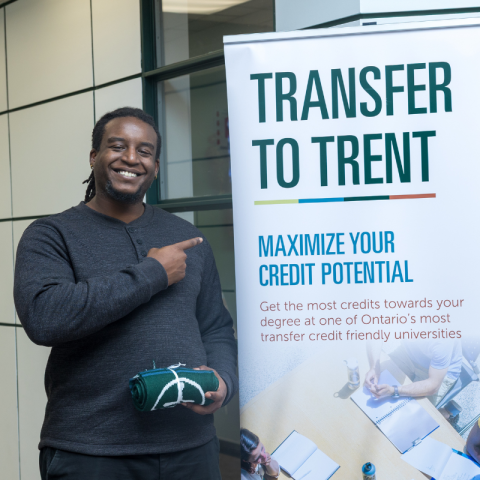 Trent staff pointing at a Transfer to Trent sign