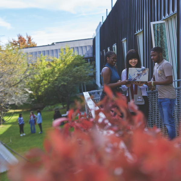Students talk outside on a balcony on campus