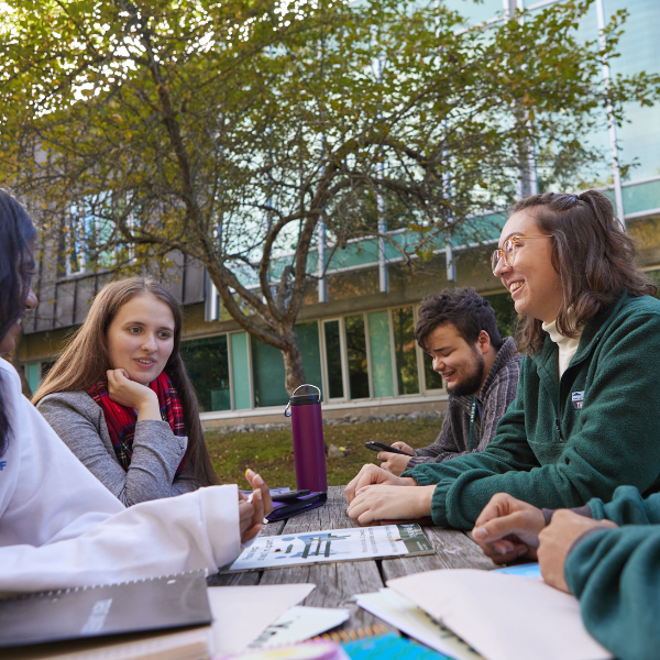 Students with papers on a picnic table discussing 