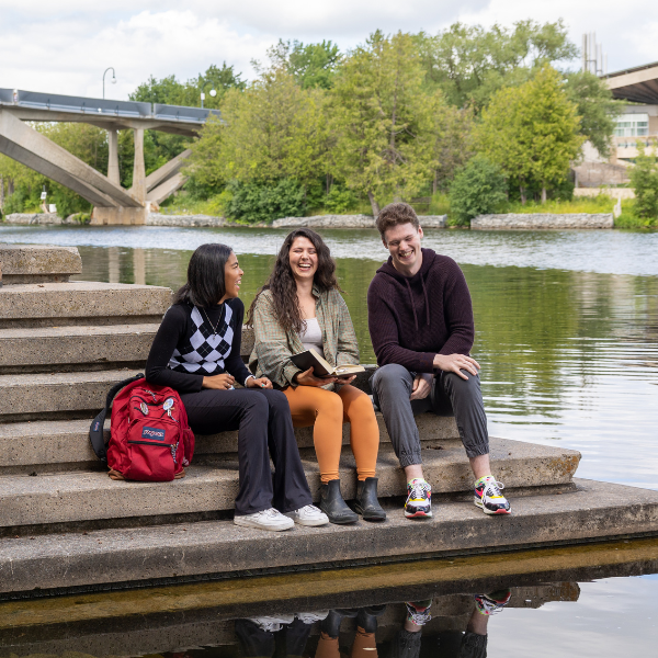 Three students sitting on bata library steps together.