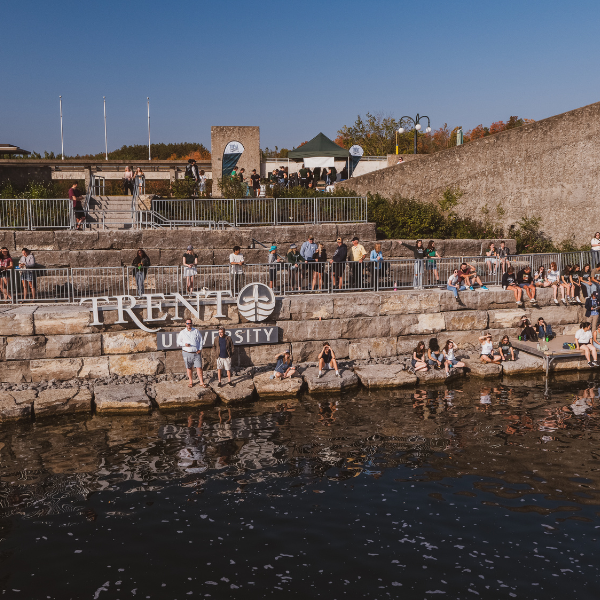 Waterfront sign and walkway with people gathered