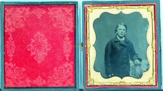 A folded frame is opened up to show a photograph of a young person in a coat, with gold around the photograph