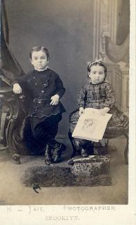 Black and white photograph of two children posing. The bottom of the photograph says H.S Tait, Photographer, Brooklyn