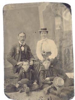 A black adn white photograph of a man, woman, and two children posing in what looks like the 19th century.