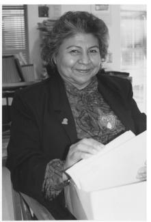 Black and white photograph of a woman smiling and holding a box of papers