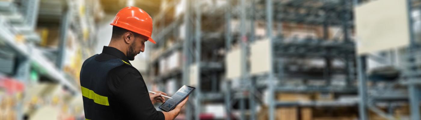 A warehouse worker using a tablet in a warehouse.