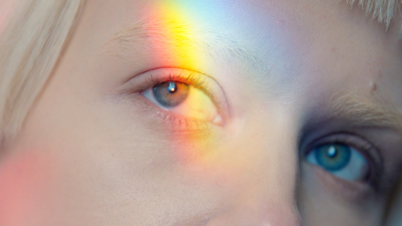 A child with a rainbow light across their eye.