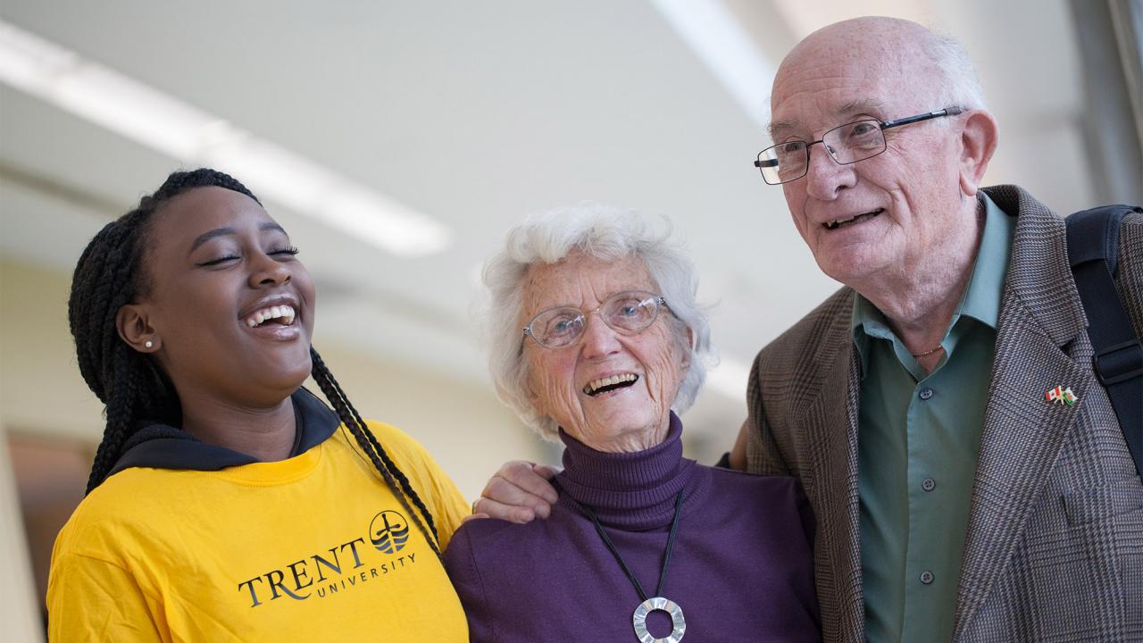 A Trent University student laughing with two seniors.