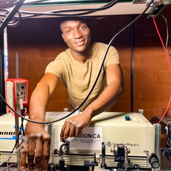 grad student working in laser lab, smiling at  camera