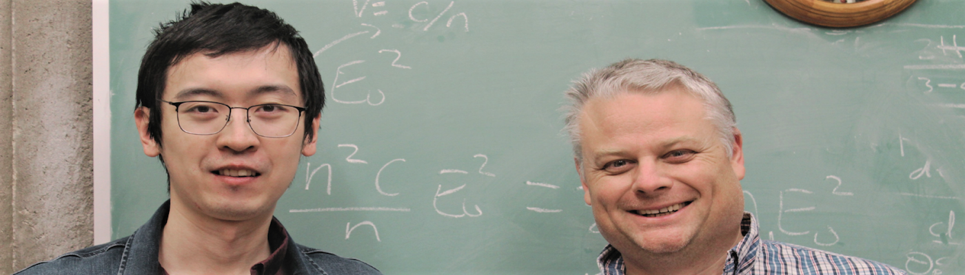 professor slepkov and student smiling in front of chalkboard