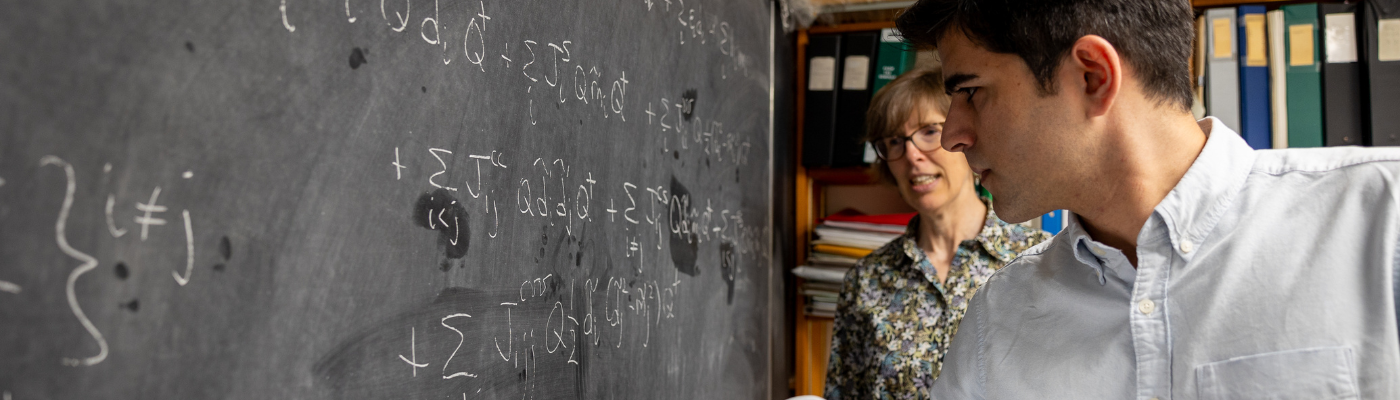 professor and student working on equation on chalkboard