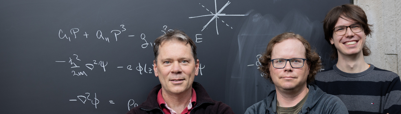 professor atkinson and 2 grad students standing in front of chalkboard