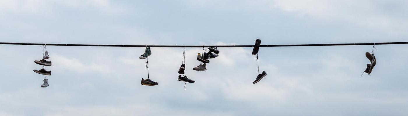 A telephone wire with 8 pairs of sneakers hung over it.