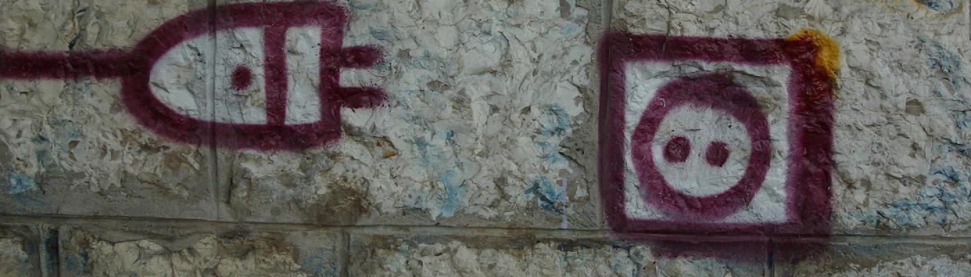  brick wall with a cord and outlet painted on it in purple.