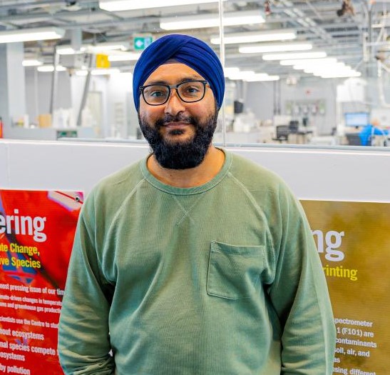 student, Davindar Panfair, smiling at camera in front of lab