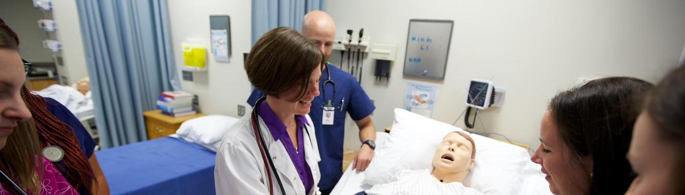 nursing instructor demonstrating skills to a small group of nursing students in a nursing lab
