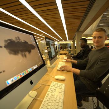 Computer screen on desk with student in background