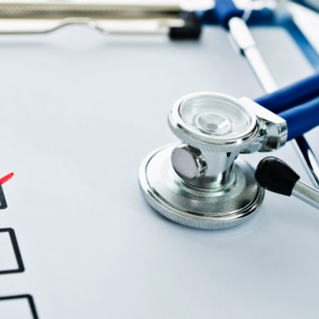 Check boxes and red check marks on a paper with a stethoscope on top.