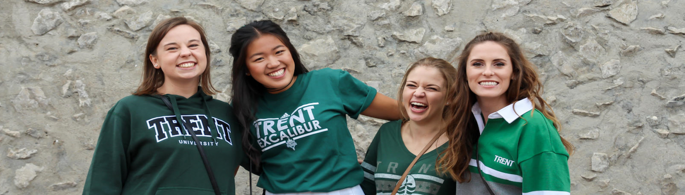 alt="Four students standing for a group photo in Trent University sweaters"