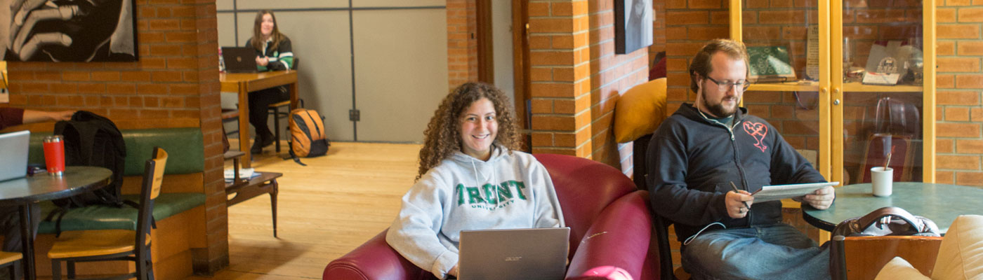 Student smiling behind laptop