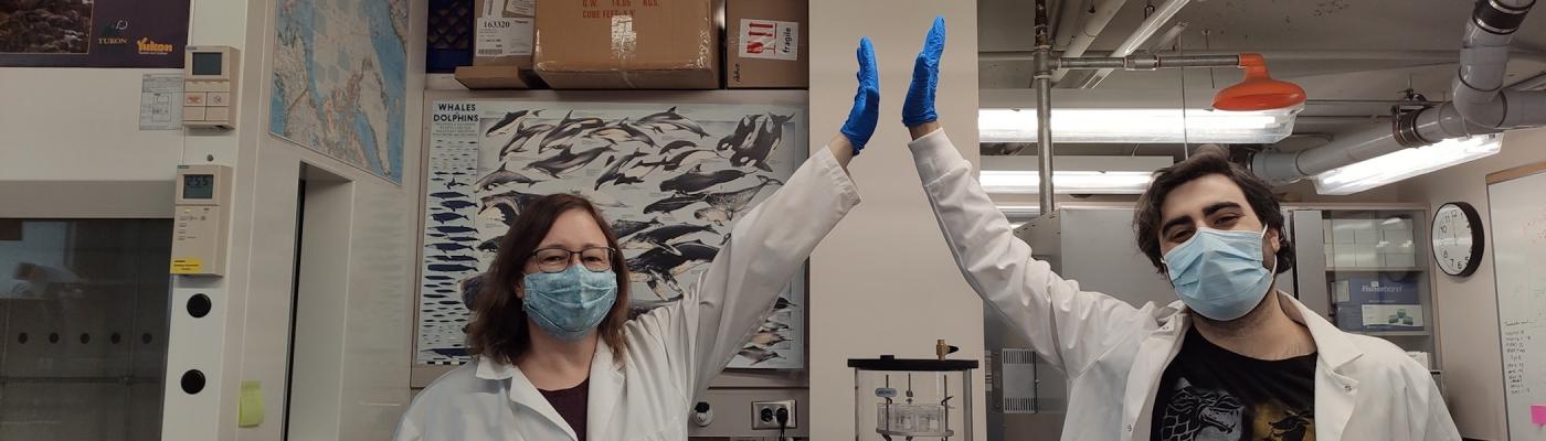 Two researchers high-fiving in a lab