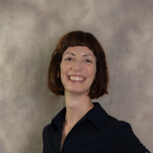 A photo of Shawna, a dark haired woman in a black top, smiling